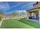 Backyard featuring an outdoor dining area, lush artificial turf, and privacy wall at 9990 Perth Ct, Las Vegas, NV 89141