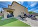 Spacious backyard with artificial grass, a covered patio, brick pavers, and comfortable seating at 9990 Perth Ct, Las Vegas, NV 89141