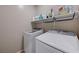 Functional laundry room with modern washer and dryer, plus overhead shelving for convenient storage solutions at 9990 Perth Ct, Las Vegas, NV 89141