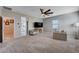 Spacious living room with neutral carpet, ceiling fan, television, and comfortable seating, ideal for relaxation and entertainment at 9990 Perth Ct, Las Vegas, NV 89141