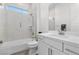 Modern bathroom with sleek white tile, a glass-enclosed shower-tub combination, and a floating vanity at 12476 Heritage Bend Dr, Las Vegas, NV 89138