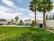 Lush backyard with a sparkling pool, rock waterfall, and mature palm trees, perfect for outdoor relaxation and recreation at 2212 Marble Gorge Dr, Las Vegas, NV 89117