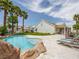 Stunning pool area with a rock waterfall, poolside seating, and palm trees, creating a resort-like atmosphere at 2212 Marble Gorge Dr, Las Vegas, NV 89117