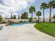 Beautiful backyard pool area with a rock waterfall feature, palm trees, and manicured landscaping at 2212 Marble Gorge Dr, Las Vegas, NV 89117