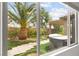 View of a backyard with a hot tub, palm tree, and stone pathway seen through a window at 3528 Tack St, Las Vegas, NV 89122
