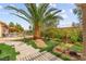 Lush backyard featuring artificial grass, manicured landscaping and a large palm tree at 3528 Tack St, Las Vegas, NV 89122