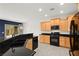 Modern kitchen with wooden cabinets, black appliances, and a breakfast bar overlooking the living area at 3528 Tack St, Las Vegas, NV 89122