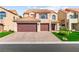Two-story home featuring a tile roof, tan stucco exterior, and a paved driveway leading to a two-car garage at 5492 Royal Vista Ln, Las Vegas, NV 89149