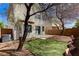 The home's private backyard features a stucco wall, concrete patio, artifical grass, and mature trees at 6267 Dollar Bill Ct, Las Vegas, NV 89141