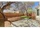 A tranquil backyard featuring a concrete patio, mature trees, brick perimeter, and artificial grass at 6267 Dollar Bill Ct, Las Vegas, NV 89141