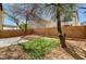 A private backyard featuring a concrete patio, brick perimeter, mature trees, and artifical grass at 6267 Dollar Bill Ct, Las Vegas, NV 89141