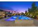A luxurious backyard features a sparkling pool and jacuzzi, surrounded by lush greenery and ambient lighting at 7477 Triple Knot Ct, Las Vegas, NV 89113