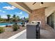 Covered outdoor patio with stone fireplace overlooking a stunning pool and backyard area at 7477 Triple Knot Ct, Las Vegas, NV 89113