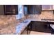 Kitchen with granite countertops, stainless steel sink, and dark wood cabinets at 7788 Ebro Valley Ct, Las Vegas, NV 89113
