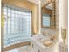 Stylish bathroom with a unique glass block window, modern fixtures, and a decorative gold-tone mirror at 8109 Moonstone Cir, Las Vegas, NV 89128