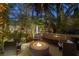 Outdoor kitchen area features pizza oven, a fire pit, and ambient lighting in a tropical landscape at 8109 Moonstone Cir, Las Vegas, NV 89128