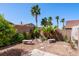 Landscaped backyard with desert plants, palm trees, stone benches, and decorative bridge at 853 Ashford Way, Henderson, NV 89015
