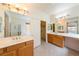 Bathroom featuring dual sinks, wooden cabinets, and large mirrors reflecting natural light at 853 Ashford Way, Henderson, NV 89015
