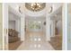 Bright foyer with a chandelier, pillars, and tile flooring leading to the living area and staircase at 2285 Villefort Ct, Las Vegas, NV 89117