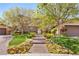 Inviting front entrance with a brick pathway surrounded by colorful flowers and lush greenery at 2285 Villefort Ct, Las Vegas, NV 89117