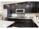 Spacious kitchen with dark wood cabinetry, stainless steel appliances, and granite countertops at 7137 Flowering Rose Ave, Las Vegas, NV 89117