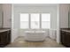 A modern bathroom with a soaking tub situated beneath a window, dual vanities, and stylish fixtures at 8863 Italian Trotter Ct, Las Vegas, NV 89113