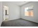 This bedroom features neutral gray carpet, a bathroom, and a view from the window at 8863 Italian Trotter Ct, Las Vegas, NV 89113