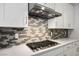 Close-up of a modern gas stovetop with a sleek backsplash and stylish range hood at 8863 Italian Trotter Ct, Las Vegas, NV 89113