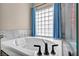 Bright bathroom featuring a large soaking tub with marble backsplash and glass block window at 90 Ancient Hills Ln, Henderson, NV 89074
