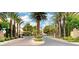 Community entrance with palm trees, flowers, security gate, and stone signage at 9705 Floweret Ave, Las Vegas, NV 89117