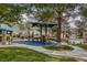 Community playground featuring slides and shade structure next to pool, set amongst mature trees at 9705 Floweret Ave, Las Vegas, NV 89117