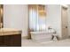 Stylish bathroom featuring a free-standing tub, unique light fixture, and tan curtains at 15 Vintage Canyon St, Las Vegas, NV 89141