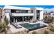 A luxurious modern backyard oasis with a pool, hot tub, lounge area, and desert landscaping at 29 Falling Ridge Ln, Henderson, NV 89011