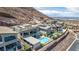 An aerial view shows modern homes with pools nestled in the hills with city views beyond at 302 Watteau Ct, Henderson, NV 89012
