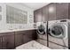 Well-organized laundry room with washer, dryer, cabinets, sink, and a window at 302 Watteau Ct, Henderson, NV 89012