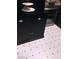 Black kitchen cabinet with silver handles and white tiled flooring with black accents at 3151 Soaring Gulls Dr # 2035, Las Vegas, NV 89128