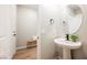 A powder bathroom features a pedestal sink, round mirror, and modern black fixtures at 3525 Serravalle Ln, Henderson, NV 89044