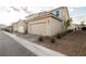 Exterior view of a beige home with a two-car garage and a gravel landscaped yard at 3525 Serravalle Ln, Henderson, NV 89044