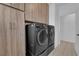 Modern laundry room with front-loading washer and dryer and wooden cabinets for supplies at 45 Via Di Mello, Henderson, NV 89011