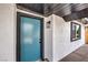 View of the bright turquoise front door, set against the white textured exterior and black trim at 4957 E Harmon Ave, Las Vegas, NV 89121