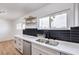 Renovated kitchen featuring a stainless steel sink, quartz countertops, a black backsplash, and floating shelves at 4957 E Harmon Ave, Las Vegas, NV 89121