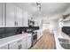 Spacious updated kitchen featuring stainless appliances, quartz countertops, a black backsplash, white cabinets, and wood-look floors at 4957 E Harmon Ave, Las Vegas, NV 89121