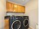 Laundry room featuring wood cabinetry with black front load washer and dryer at 504 Landra Ln, Henderson, NV 89015