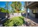 A manicured backyard features synthetic grass, stone planters, and an outdoor kitchen area for outdoor entertaining at 580 Via Di Parione Ct, Henderson, NV 89011