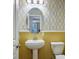 Bathroom featuring yellow accent wall, patterned wallpaper, stylish mirror, and modern fixtures at 580 Via Di Parione Ct, Henderson, NV 89011
