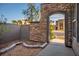 View through the arched stone entrance to a private courtyard with stone accents and lush landscaping at 580 Via Di Parione Ct, Henderson, NV 89011