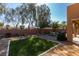 Landscaped backyard with artificial turf, decorative rock, mature trees, and partial privacy wall at 6470 Crest Estates St, Las Vegas, NV 89131