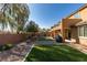 Spacious backyard boasting artificial turf, decorative rock, mature trees, and partial privacy wall at 6470 Crest Estates St, Las Vegas, NV 89131