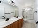 Bright bathroom features double sinks, wood cabinets, and a glass enclosed shower-tub combination at 6973 Pacific Coast St, Las Vegas, NV 89148