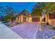 Beautiful home exterior featuring a brick driveway, lush landscaping, and a three-car garage at 7 Hilltop Crest St, Henderson, NV 89011